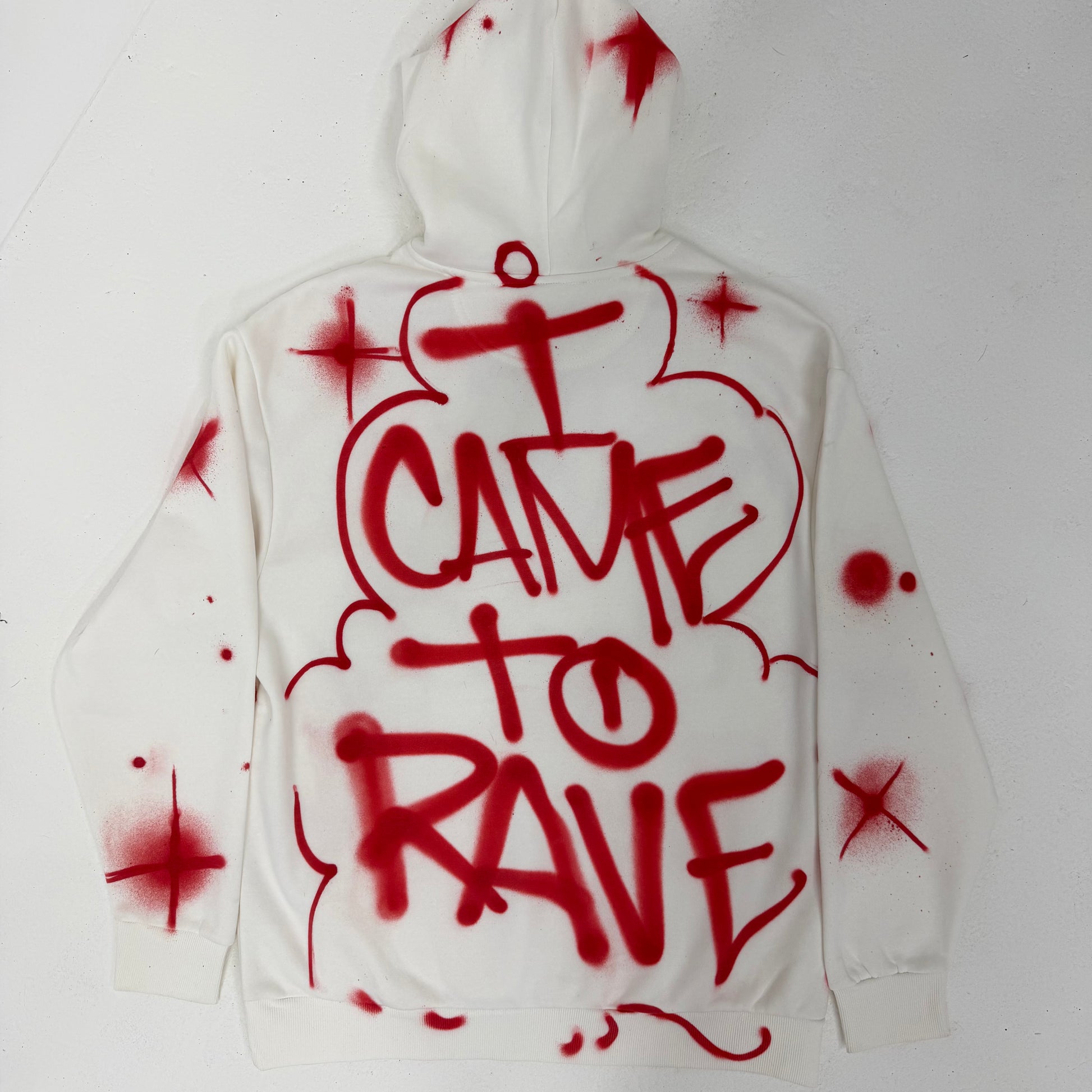 White hoodie with red spray paint text on a white background
