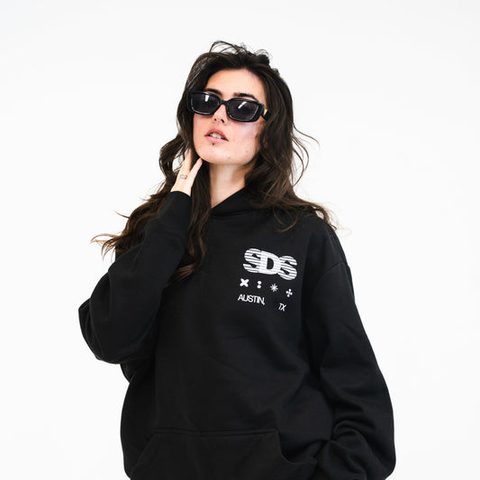 Person wearing a black hoodie with 'SDS' logo and lace pants on a white background
