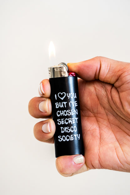 Hand holding a lighter with text 'I ❤️ you but I've chosen Secret Disco Society' against a white background